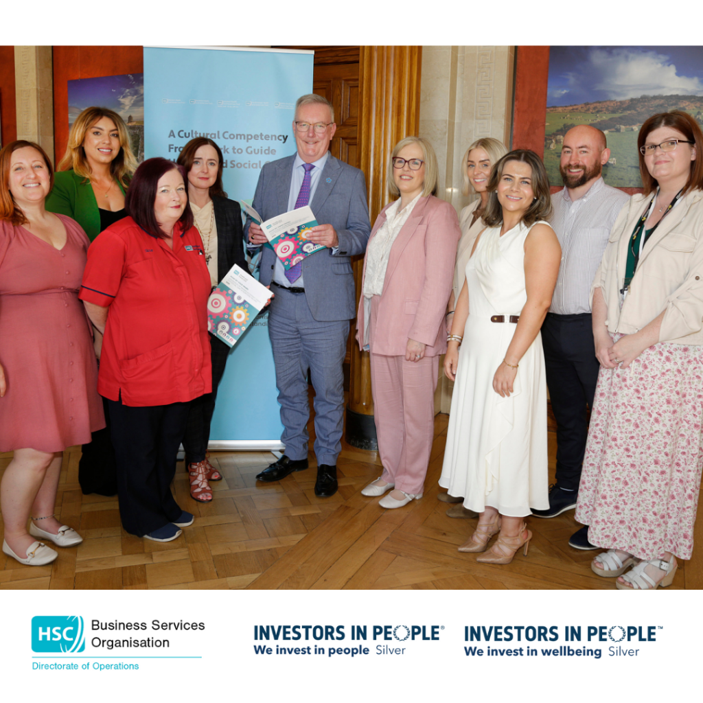 Health Minister Mike Nesbitt holding a report with the steering group of the report. All standing in front of a pull-up banner